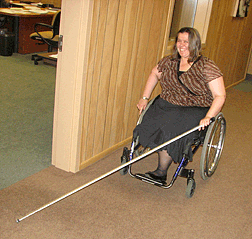 In order to safely travel and detect obstacles well in advance, Treva chooses to use a straight sixty-one-inch carbon fiber cane. Treva uses both hands on the wheels of her chair, while using one hand to also grasp her cane.