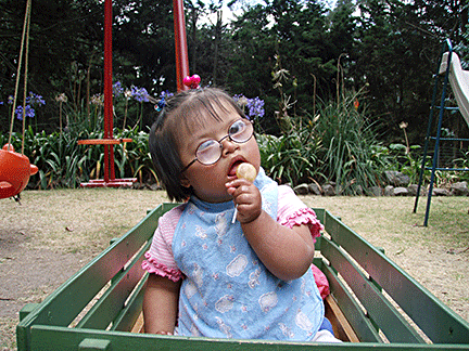 Grace sits in a wagon holding a lollipop. See article: Finding Our Way with Grace