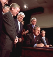 President George Bush, surrounded by staff, signs the Help America Vote Act on October 29, 2002.