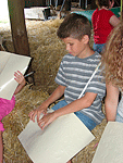 Boy reading Braille on a hay bail
