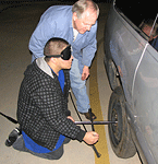 Boy in sleep shades changing the tire on an automobile