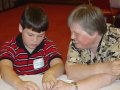 A blind boy reads Braille with the help of a blind adult.